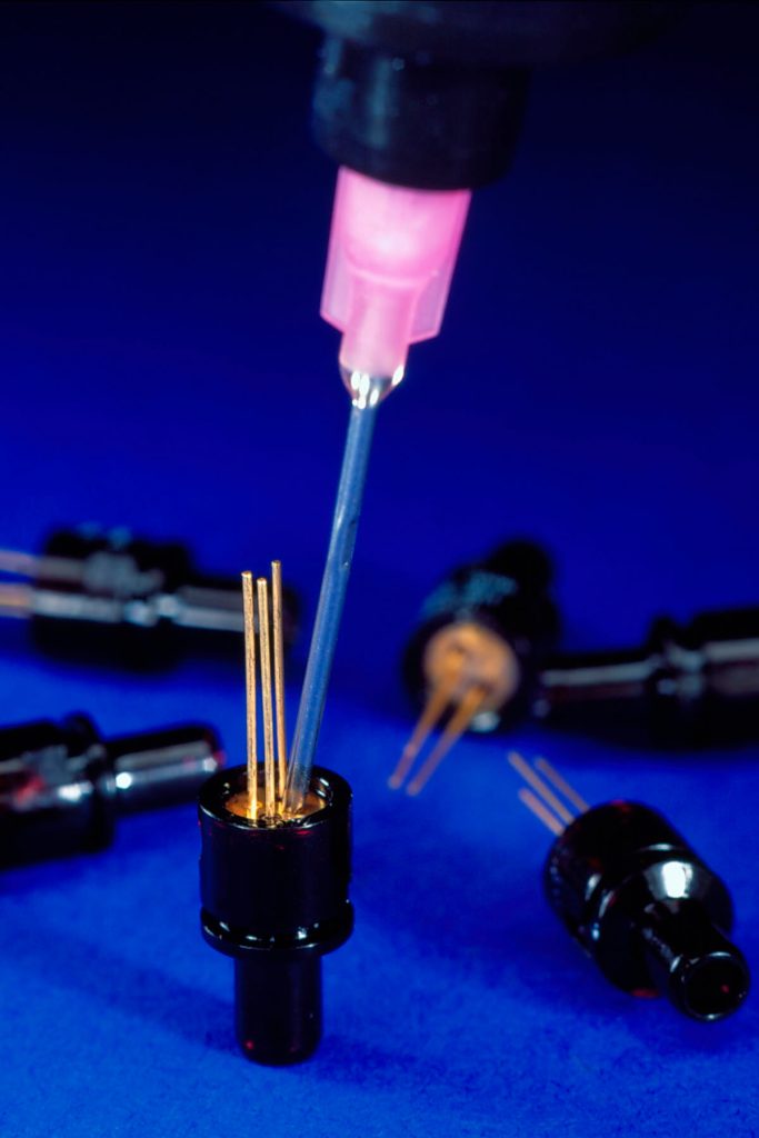 Low shrinkage adhesive for optical assembly eliminates parts movement