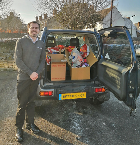 James stands proudly next to a vehicle full of foodbank donations