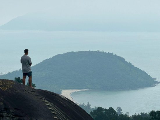 Liam standing on a hill overlooking a misty vista in southeast Asia
